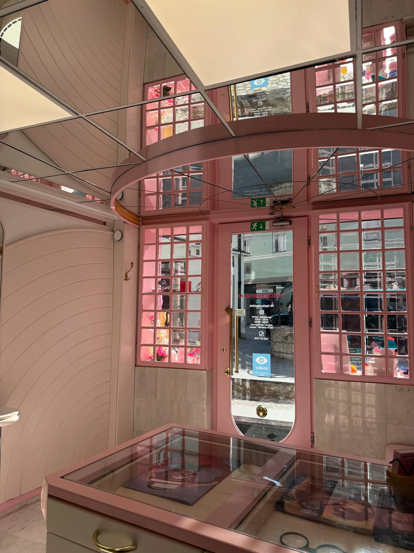Notranjost optike Mostiček — rožnata vrata in vitrine z očali